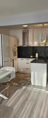 a kitchen with white cabinets and a black counter top at Апартамент ЛазуР in Burgas City