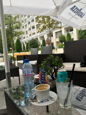 a table with a cup of coffee and a bottle of water at Seaside View Apartment in Varna in Varna City