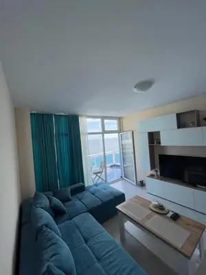 a living room with a blue couch and a table at Апартамент Лариди in Sozopol