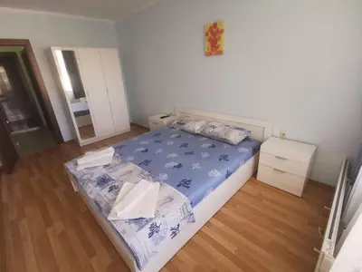 a bedroom with a bed with a blue comforter at Апартамент ЛаХабана до плажа в Поморие in Pomorie