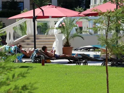 two men laying in lawn chairs under an umbrella at Sunrise Luxury Sauth Bay in Varna City
