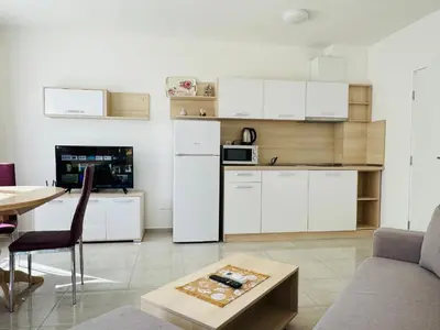 a kitchen with white cabinets and a table in a room at HORIZON 12 'Б' Apartment Sveti Vlas in Sveti Vlas