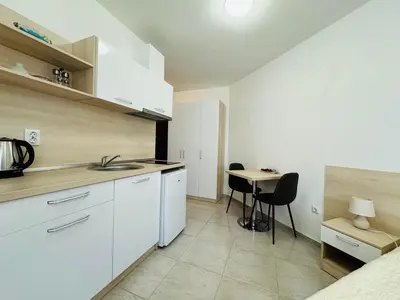 a kitchen with white cabinets and a table with chairs at HORIZON 11 'Б' Studio Sveti Vlas in Sveti Vlas