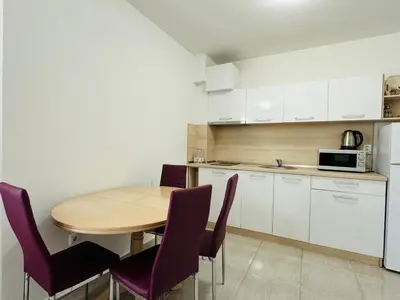 a kitchen with a wooden table and purple chairs at HORIZON 10 'Б' Apartment Sveti Vlas in Sveti Vlas