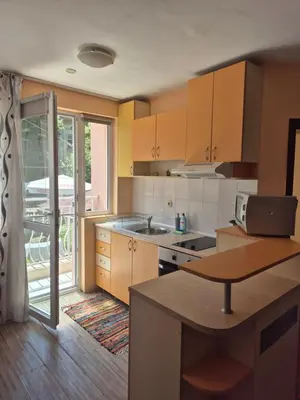 a kitchen with wooden cabinets and a kitchen island with a table at YES Varna Studios in Varna City