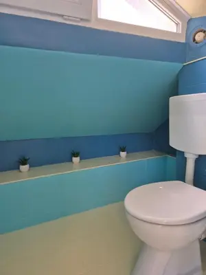 a bathroom with a white toilet and blue walls at YES Varna Studios in Varna City