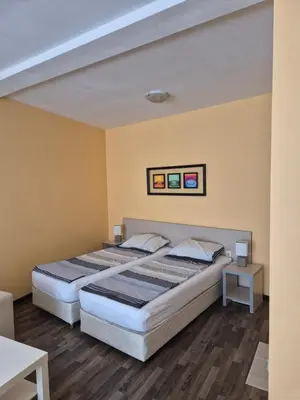 two beds in a room with yellow walls and wooden floors at YES Varna Studios in Varna City