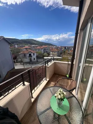 a glass table with a vase of flowers on a balcony at Апартамент 