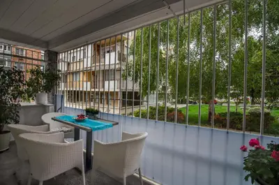 a balcony with white chairs and a table and windows at Apartment Bellissima 2 minutes away from the beach in Nesebar