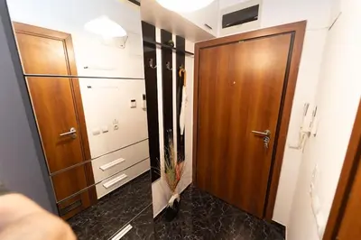 a bathroom with a wooden door and a black floor at Апартамент за гости Уют in Burgas City