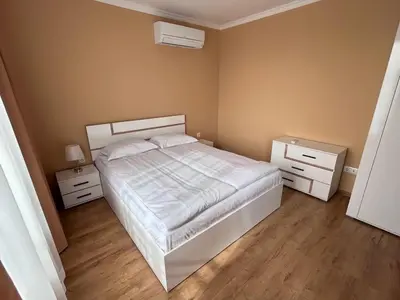 a bedroom with a white bed and two night stands at Апартаменти Bella Deluxe in Ravda