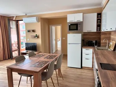 a kitchen and dining room with a table and a refrigerator at Апартаменти Bella Deluxe in Ravda