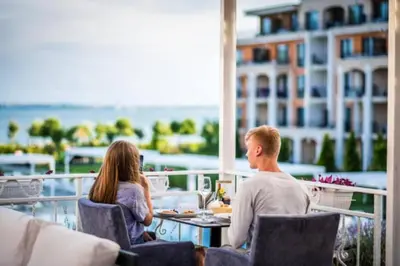 a man and a woman sitting at a table on a balcony at Premier Fort Apartment on Seafront in Sveti Vlas