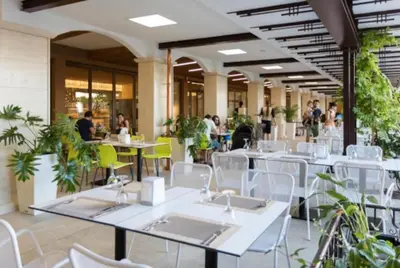 a restaurant with white tables and chairs and people sitting at tables at Premier Fort Apartment on Seafront in Sveti Vlas
