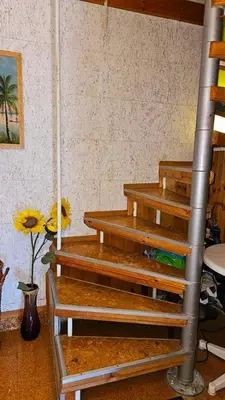 a stack of wooden stairs in a room with a vase of flowers at Хоризонт in Nesebar