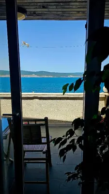a view of a beach from a window with a bench at Хоризонт in Nesebar