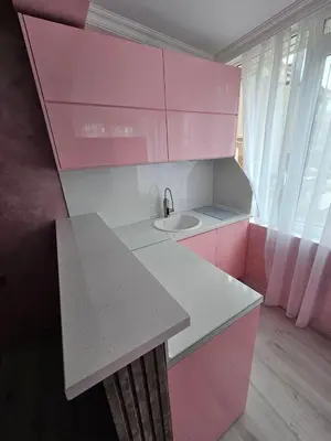 a pink and white kitchen with a sink and a counter at Апартамент Елинор in Pomorie