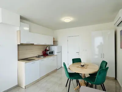 a kitchen with a table and green chairs in a room at HORIZON 9 'В' Apartment Sveti Vlas in Sveti Vlas