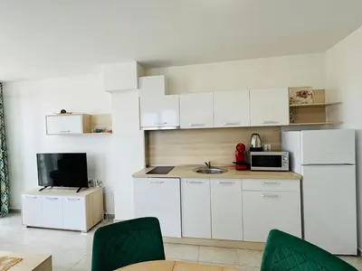 a small kitchen with white cabinets and a tv at HORIZON 2 'В' Apartment Sveti Vlas in Sveti Vlas