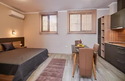 a bedroom with a bed and a table and a kitchen at Bendita House in Pomorie
