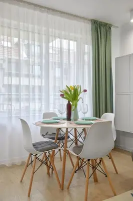 a dining room table with white chairs and a vase of flowers at Sea Moreto Studio 1 in Burgas City