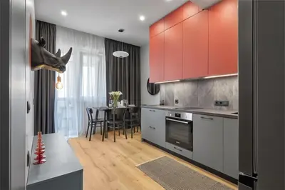 a kitchen with red cabinets and a dining table at Sea Moreto Apartment 2 in Burgas City