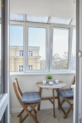 a table and two chairs in a room with windows at Sea Moreto Apartment 2 in Burgas City
