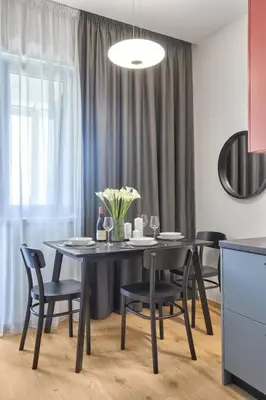 a dining room table with black chairs and a table with flowers at Sea Moreto Apartment 2 in Burgas City