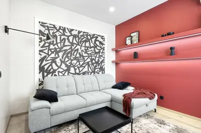 a living room with a couch and a red wall at Sea Moreto Apartment 2 in Burgas City