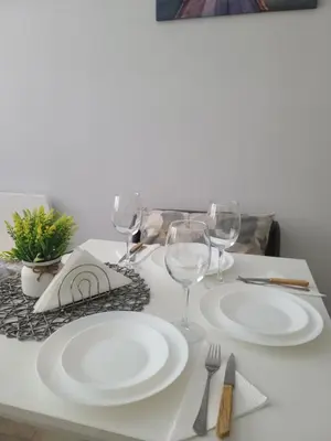 a table with white plates and wine glasses on it at Downtown Apartment Varna in Varna City