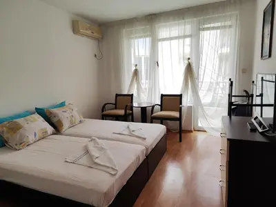 a bedroom with two beds and a desk and windows at Nev in Burgas City