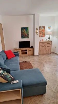 a living room with a blue couch and a tv at Pomorie Chaika Home in Pomorie