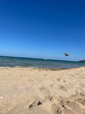 a sandy beach with a kite flying over the ocean at Good Mood Studio in Green Life First Line in Sozopol