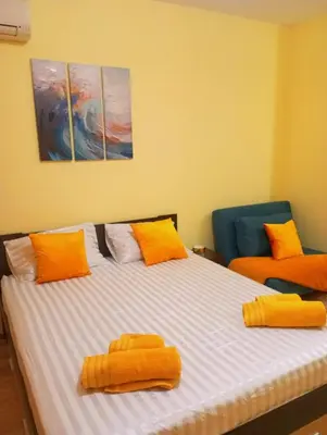 a bedroom with a large bed with orange pillows at One-room boutique at Sunrise All Suites in Obzor