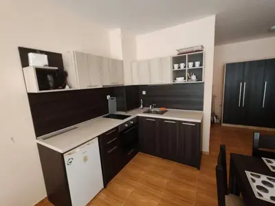 a kitchen with black and white cabinets and wooden floors at Magic Dreams Apartments in Sveti Vlas