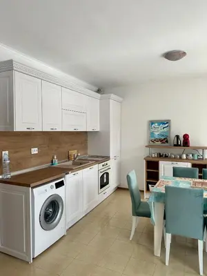 a kitchen with a washing machine and a table with chairs at Seaside Apartment Nesebar in Nesebar