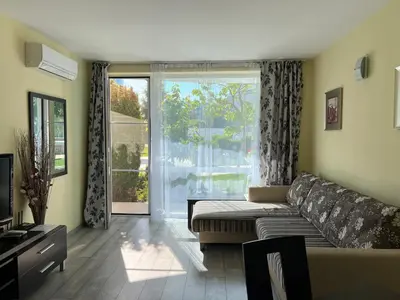 a living room with a couch and a large window at Apartment with terrace in Spa Complex in Burgas City