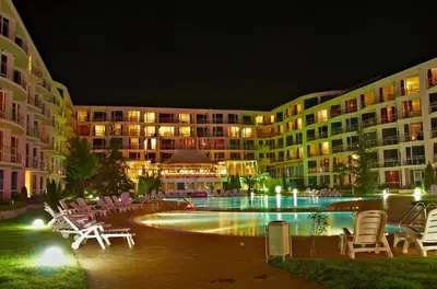 a courtyard with chairs and a swimming pool at night at Apartment with terrace in Spa Complex in Burgas City