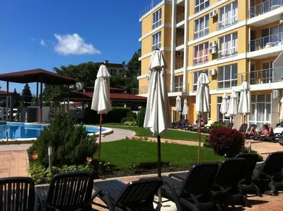 a group of white umbrellas and chairs next to a building at Reina Apart Flores Park in Sunny Beach