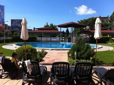 a man sitting in lawn chairs next to a pool at Reina Apart Flores Park in Sunny Beach