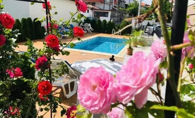 a swimming pool with pink flowers in front of it at Апартамент за гости ДЕНИЦА in Obzor