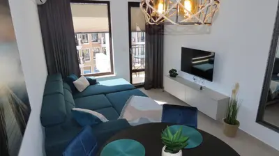 a living room with a blue couch and a table at Polarstar Apartment Verona in Sveti Vlas