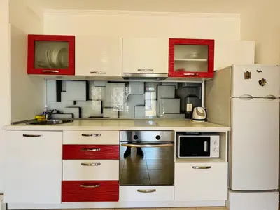 a small kitchen with white appliances and red cabinets at VODENICATA 3 Apartament Sveti Vlas in Sveti Vlas