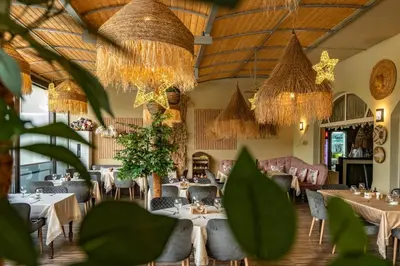 a dining room with tables and chairs and chandeliers at Хотел и Вили Марая in Tsarevo