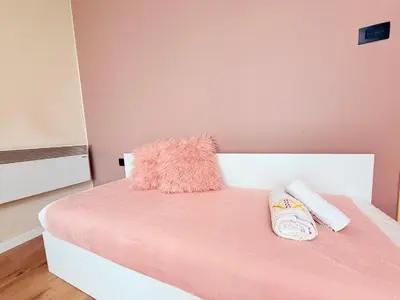 a pink bedroom with a pink bed with two pillows at 