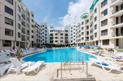 a large swimming pool with white chairs and buildings at Avalon studio,Sunny Beach in Sunny Beach