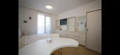 a white kitchen with a white table in a room at Студио Сарафово in Burgas City