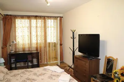 a room with a bed and a desk and a television at Супер апартамент-център Варна in Varna City