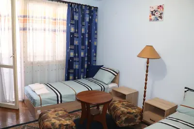 a room with two beds and a table and a chair at Супер апартамент-център Варна in Varna City
