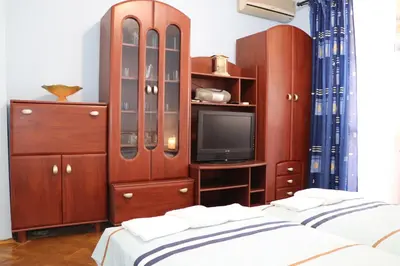 a bedroom with two beds and a tv and wooden cabinets at Супер апартамент-център Варна in Varna City